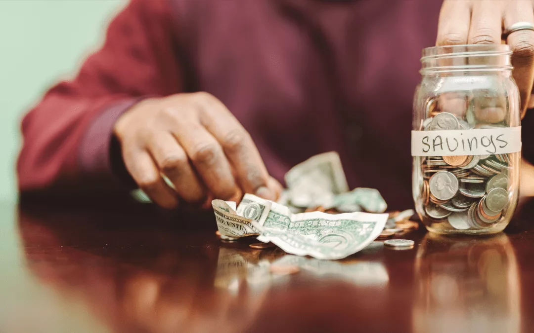 person reaching in savings jar