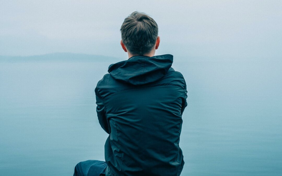 man looking out over ocean on a foggy day